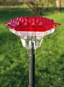 A red bird feeder sitting on top of a pole.