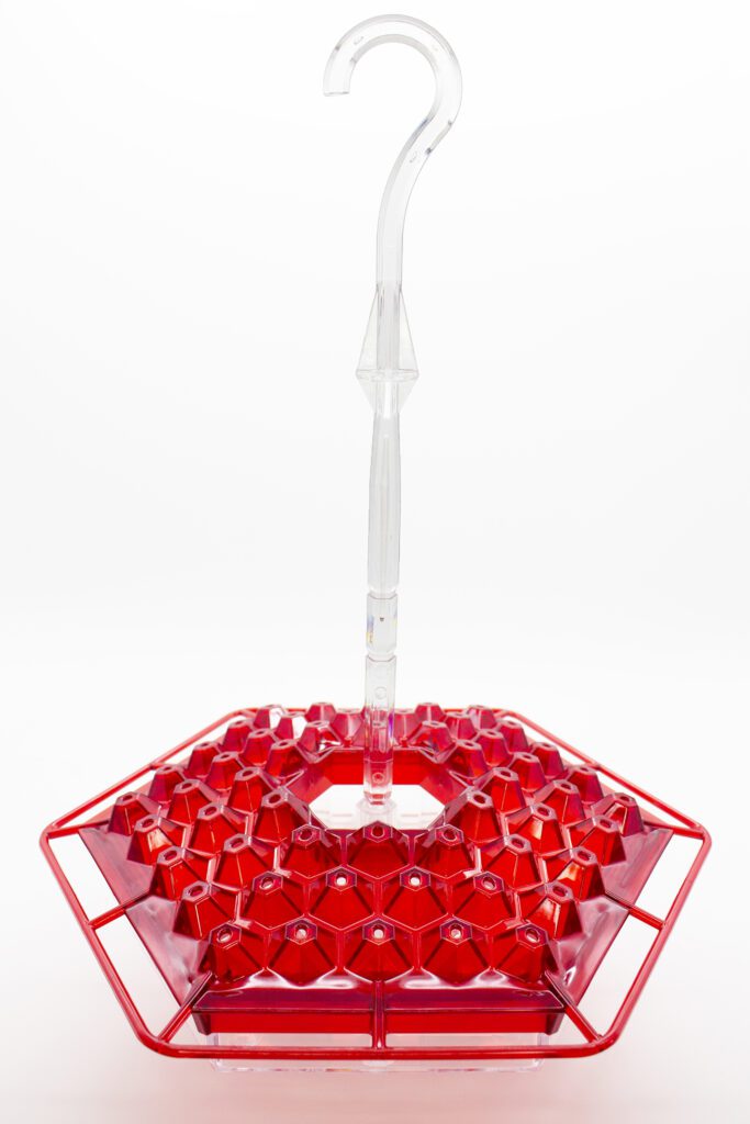 A red plastic container with a handle on top of it.